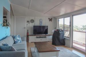 a living room with a couch and a flat screen tv at The Shack at Black Head in Hallidays Point