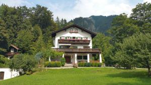 a house in the middle of a field with trees at Pension Villa Bergkristall in Eschenlohe