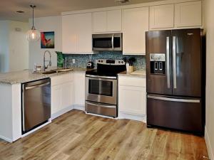 Una cocina con electrodomésticos de acero inoxidable y gabinetes blancos. en Sea You Soon, en Rockport