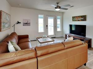 sala de estar con sofá de cuero marrón y TV de pantalla plana en Sea You Soon, en Rockport