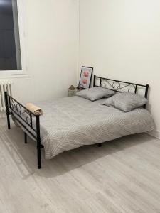 a bed with a black frame and a chair in a bedroom at Appartement spacieux au centre-ville in Montluçon
