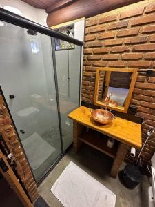 a bathroom with a sink and a glass shower at Cabana Fé Miguel Pereira Chalé Para Casal no Centro MP in Miguel Pereira