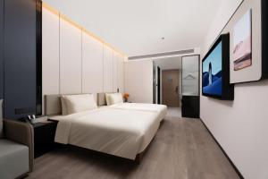 西安市にあるAtour Hotel Xi'an North Railway Station Hongqichang Subway Stationの大きな白いベッドとテレビのある寝室