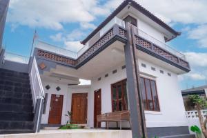 a white house with a staircase in front of it at Aurora Holiday House Kintamani in Kintamani