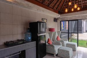 a kitchen with chairs and a refrigerator and a fireplace at Aurora Holiday House Kintamani in Kintamani