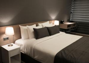 um quarto com uma cama grande com lençóis brancos e almofadas em Nova Hotel Yerevan em Yerevan