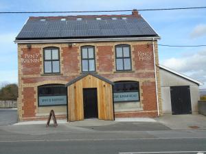 un edificio de ladrillo con paneles solares encima en Kings Head en Capel Hendre