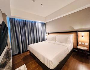 a bedroom with a white bed and a window at d'primahotel Airport Sultan Hasanuddin Makassar in Sudiang