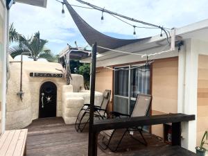 a patio with chairs and a hammock on a house at 8人乗りレンタカー無料ファミリー団体向け貸別荘珊瑚のサウナ in Miyako Island