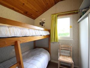 1 Schlafzimmer mit 2 Etagenbetten und einem Stuhl in der Unterkunft Pavillon calme avec jardin clos, animaux admis, parking, à 2 km du centre de La Bourboule - FR-1-415-156 in La Bourboule