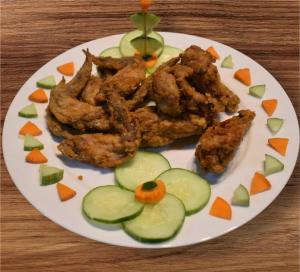 a plate of food with chicken and cucumbers and carrots at KJT Travellers Inn in Guindulman