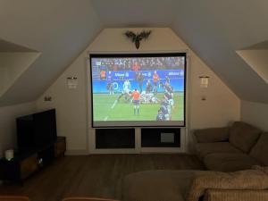 a living room with a large tv in the attic at Dukes Flat in Ampney Saint Peter