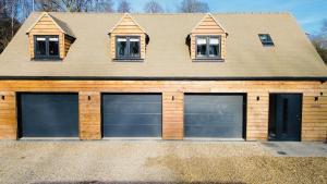 a house with two garage doors in front of it at Dukes Flat in Ampney Saint Peter