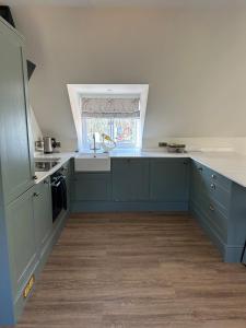 a kitchen with blue cabinets and a sink and a window at Dukes Flat in Ampney Saint Peter +7 photos