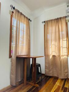 a wooden table in a room with curtains at Silver Sand, Placencia in Placencia Village