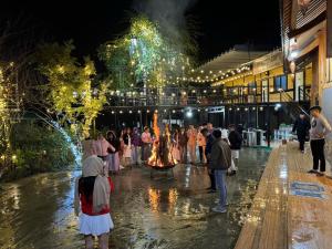 eine Gruppe von Menschen, die nachts um ein Feuer stehen in der Unterkunft Plum Homestay in Dồng Văn