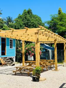 a wooden pergola with a picnic table in front of a house at Silver Sand, Placencia in Placencia