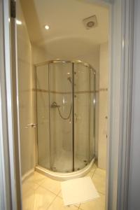 a glass shower in a bathroom with a tile floor at Ridgemount Hotel in London
