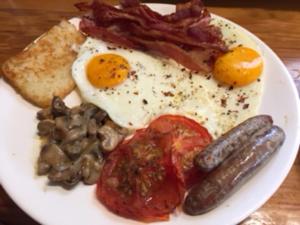 a plate of breakfast food with eggs bacon and mushrooms at Anglesea House Inn in Renwick