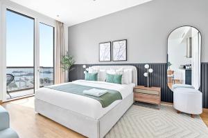 une chambre blanche avec un grand lit et un miroir dans l'établissement Silkhaus cozy Studio at Al Bandar Marina with gym, à Abu Dhabi