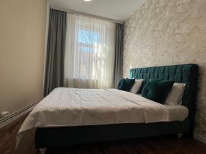 a bedroom with a bed with a green headboard and a window at Urban Waves with 2 bedrooms and terace in Constanţa