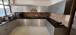 a kitchen with white cabinets and black counter tops at Rustic Homestay Sonipat in Sonīpat