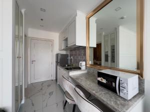 eine Küche mit weißen Schränken und einer Theke mit Stühlen in der Unterkunft The Empire Tower Pattaya in Jomtien Beach + 9 Fotos