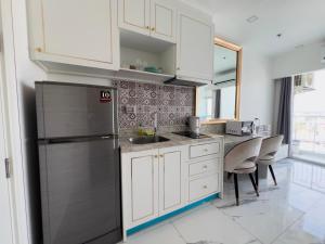 eine Küche mit weißen Schränken und einem Edelstahlkühlschrank in der Unterkunft The Empire Tower Pattaya in Jomtien Beach