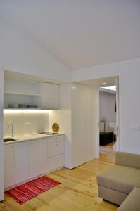 a kitchen with white cabinets and a living room at Aldeia do Priolo in Nordeste