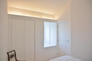 a bedroom with white walls and a bed and a chair at Aldeia do Priolo in Nordeste