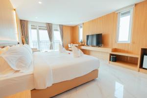 Un dormitorio con una gran cama blanca y un televisor de pantalla plana. en The Elephant Crossing Hotel, en Vang Vieng