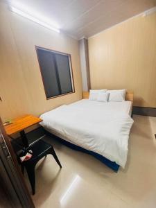 a bedroom with a large white bed and a table at Vinh Hotel in Thốt Nốt