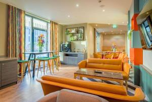 un soggiorno con mobili arancioni e una cucina di Ramada Encore by Wyndham Munich Messe a Monaco