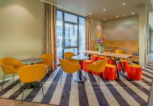 una sala d'attesa con tavolo e sedie arancioni di Ramada Encore by Wyndham Munich Messe a Monaco