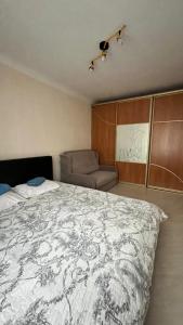a bedroom with a large bed and a chair at Saules 73 in Daugavpils
