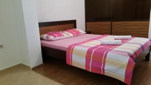 a bed with pink and white sheets and pink pillows at Apartment Milica in Petrovac na Moru