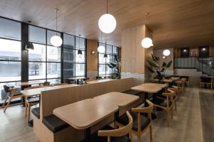 a restaurant with wooden tables and chairs and windows at Kindness Hotel - Jhong Jheng in Kaohsiung