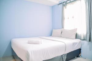 タンゲランにあるPleasant Studio at Baileys Apartment By Travelioの青い壁と窓が特徴のドミトリールームのベッド1台分です。 +14枚の写真