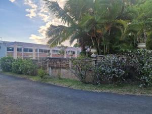 a fence in front of a building with a palm tree at Jacaranda in Saint-Louis