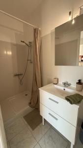 a white bathroom with a sink and a shower at Appartement intra-muros in Aigues-Mortes
