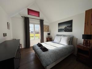 a bedroom with a large bed and a window at Maison de campagne lumineuse spacieuse dans impasse au calme a proximité d'un chateau deux vérandas grand jardin cabane pour vélos, pres Port en Bessin et Bayeux, proche plages du débarquement in Commes