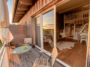 ein Balkon mit einem Glastisch und Stühlen auf einem Haus in der Unterkunft Lerchenhof Reestow - Ruhige Premium Apartments & Sauna in Reestow
