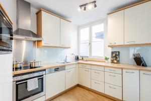 a kitchen with white cabinets and a stove top oven at GT-City Suite 03 I Balkon I Gas-Grill I Smart TV in Gütersloh