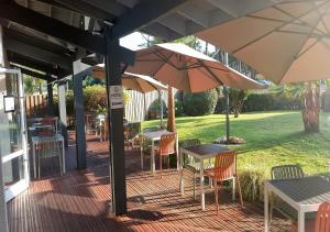 an outdoor patio with tables and chairs and umbrellas at Les Jardins de L'Ocean - Climatisé in Biscarrosse-Plage