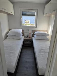 two beds in a small room with a window at Langewieke in Hollum
