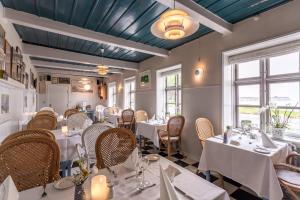 a restaurant with white tables and chairs and windows at Stevns Klint Strandpension in Rødvig
