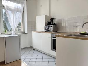 a kitchen with white cabinets and a sink and a window at Fully equipped Apartment with Balcony in Zwickau