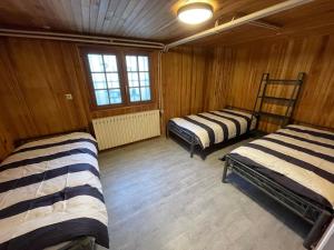 three beds in a room with wooden walls at Villa 21 couchages avec piscine interieure chauffée in Belleu +32 photos