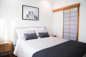 a bedroom with a white bed and a framed picture on the wall at Ellen City Centre in Fremantle