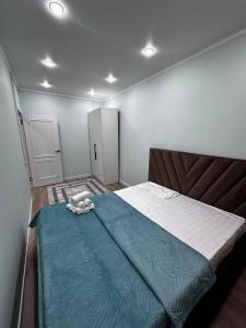 a bedroom with a bed with a blue blanket on it at ЖК Комсомольский in Astana